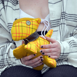 Close up of a young woman holding a handmade yellow Tweed Scottie dog.
