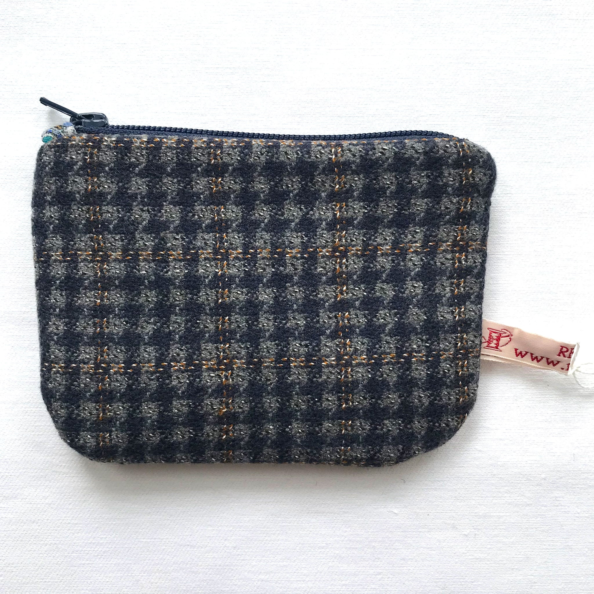 Close up of purse with blue and grey tweed. ReTweed label is showing.