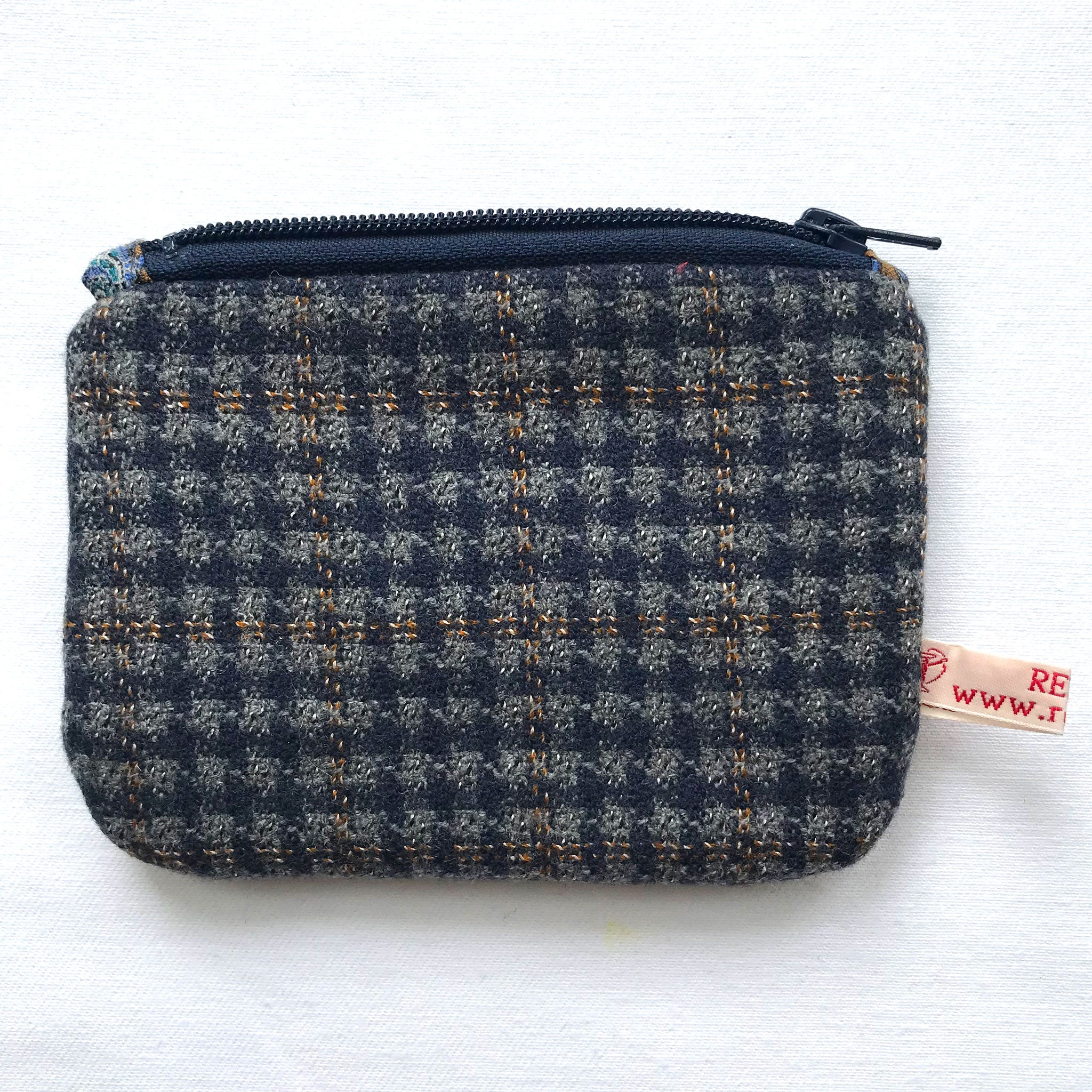 Close up of blue and grey tweed purse with navy zip. ReTweed label is visible